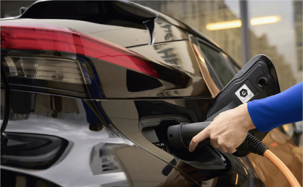 Zbliżenie na wtyczkę CCS podłączaną do gniazda czarnej Toyoty podczas ładowania w salonie Toyota Walder Zabrze